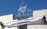 Protesters abseil down the front of Parliament House